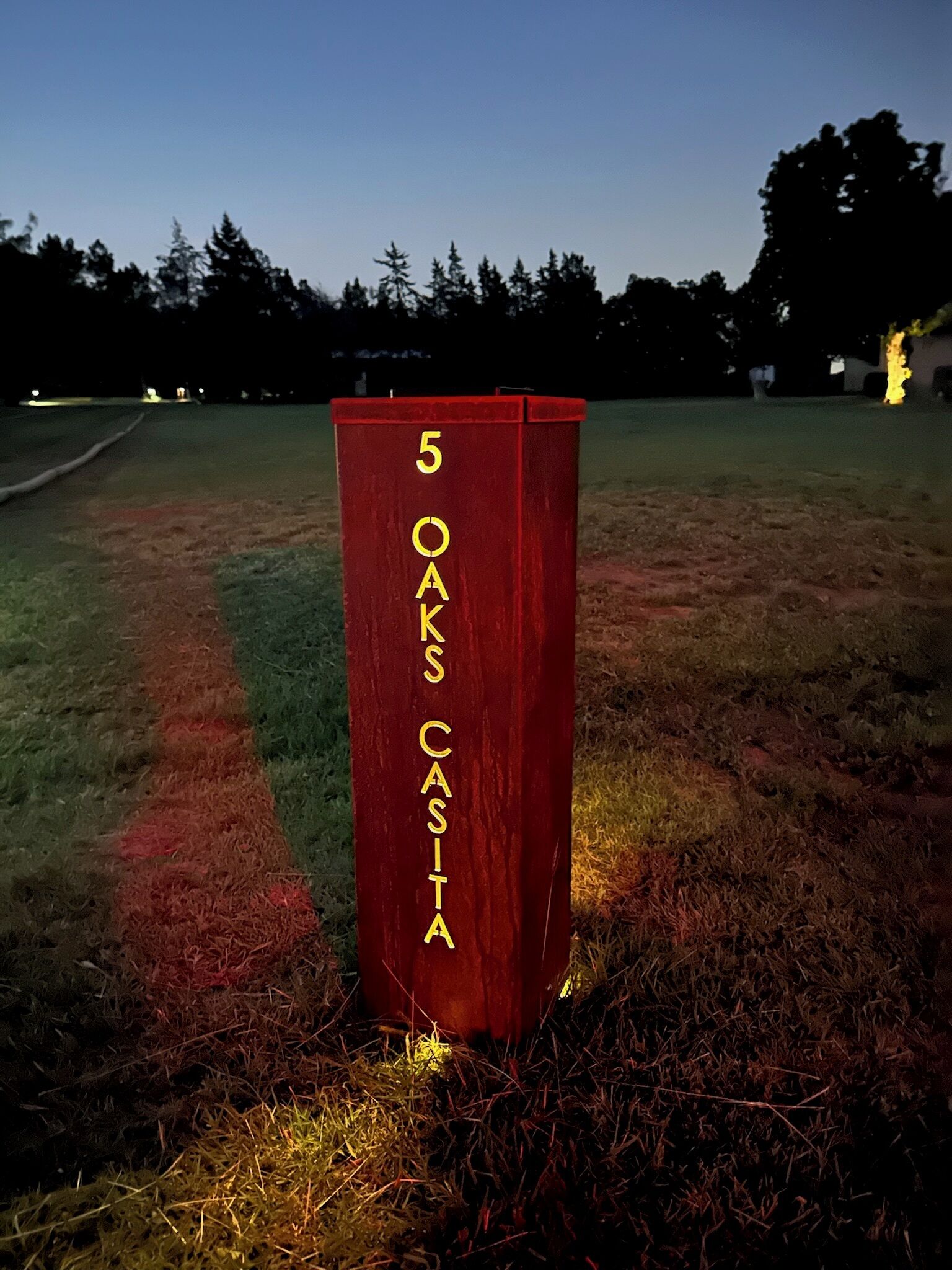 A red post with the number 5 and the text 'OAKS CASITA' on it, located in a grassy area.