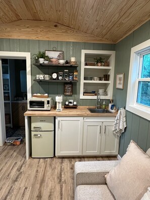 A compact kitchen with a built-in oven, a coffee maker, and a sink.