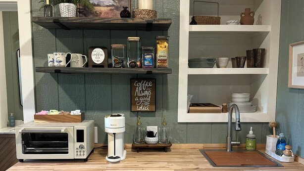 Ett litet, praktiskt kök med inbyggd ugn, kaffebryggare och kylskåp.