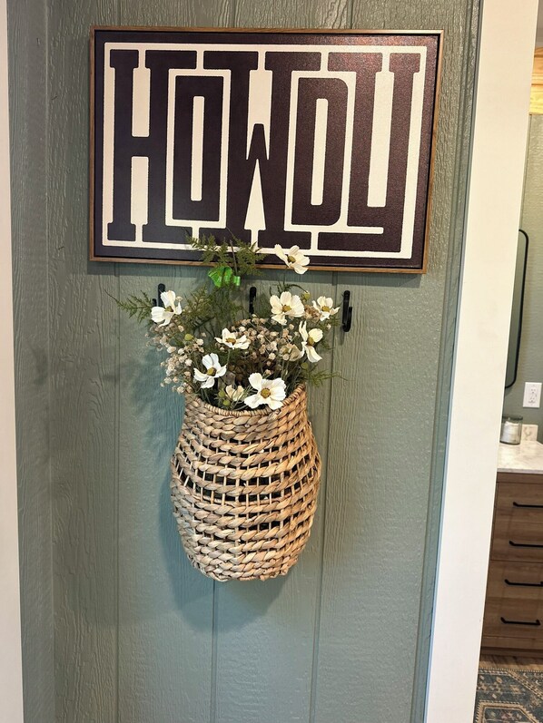 Eine Tür mit einem Schild mit der Aufschrift 'HOWOLI' und einem Korbbusch mit Blumen.