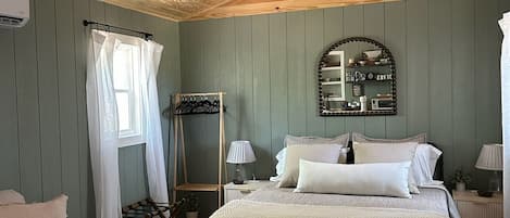 Un dormitorio acogedor con cama, mesitas de noche, una silla colgante y un ventilador de techo.