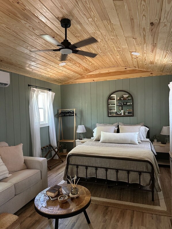 Un dormitorio acogedor con cama, mesitas de noche, una silla colgante y un ventilador de techo.