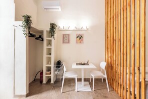 A small, well-lit room with a white table, two chairs, a shelf with decorative items, and a wooden partition. - Cori miu Home - One Bedroom Apartment, Sleeps 2 (Avola)