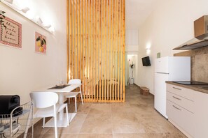 A modern kitchen with a dining area, a wooden partition, and a white refrigerator. - Cori miu Home - One Bedroom Apartment, Sleeps 2 (Avola)