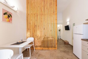 A modern kitchen with white cabinets, a white refrigerator, and a wooden partition. - Cori miu Home - One Bedroom Apartment, Sleeps 2 (Avola)