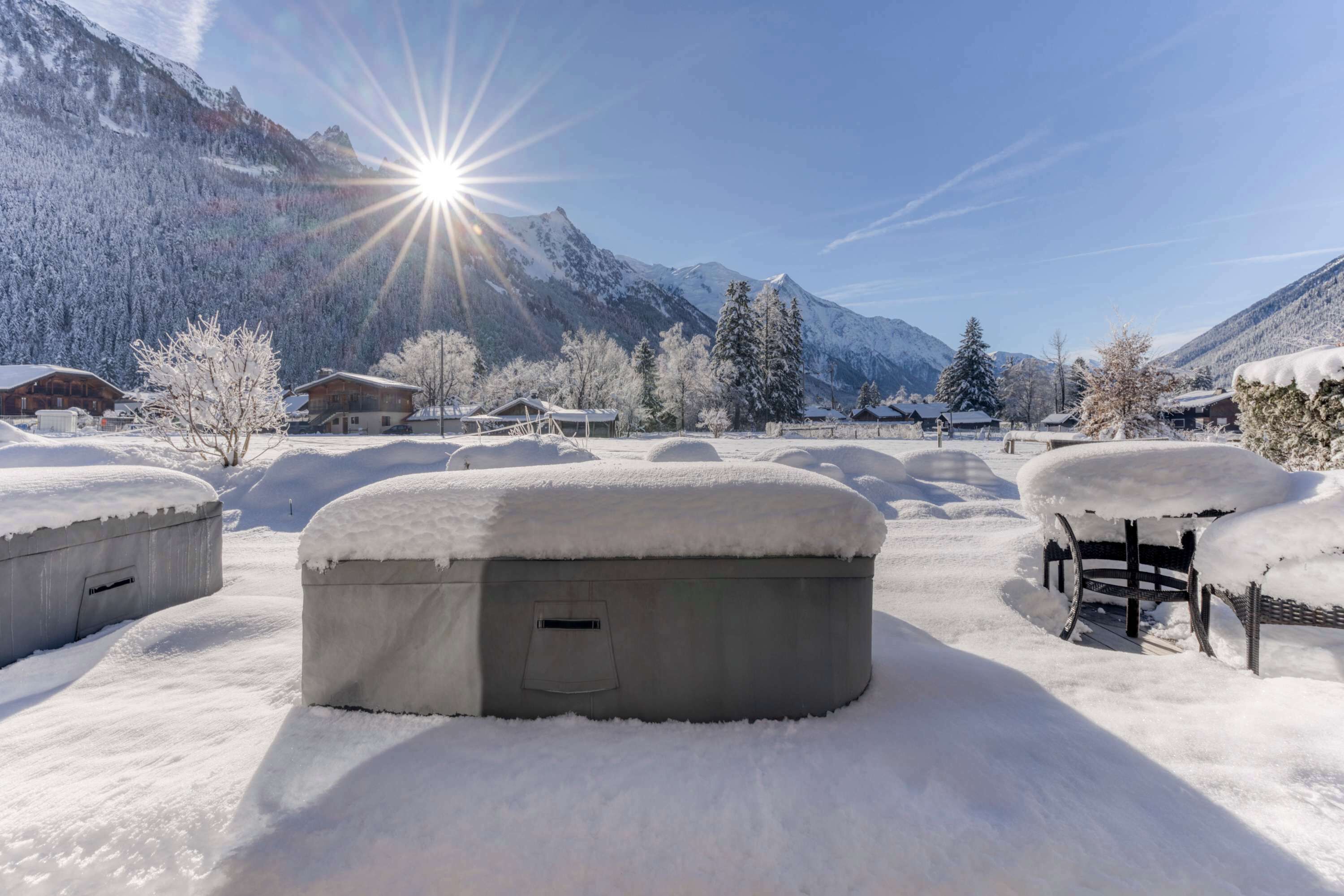 Un espace extérieur enneigé, avec des bâtiments et des montagnes en arrière-plan.