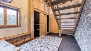 A wooden interior with a herringbone-patterned rug, a wooden bench, a staircase, and a stone wall. - Clarines · Where the Fields Meet Mont Blanc (Chamonix)