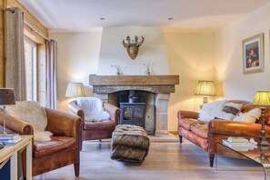 Un salon avec des canapés en cuir, une cheminée et une tête de cerf accrochée au mur.