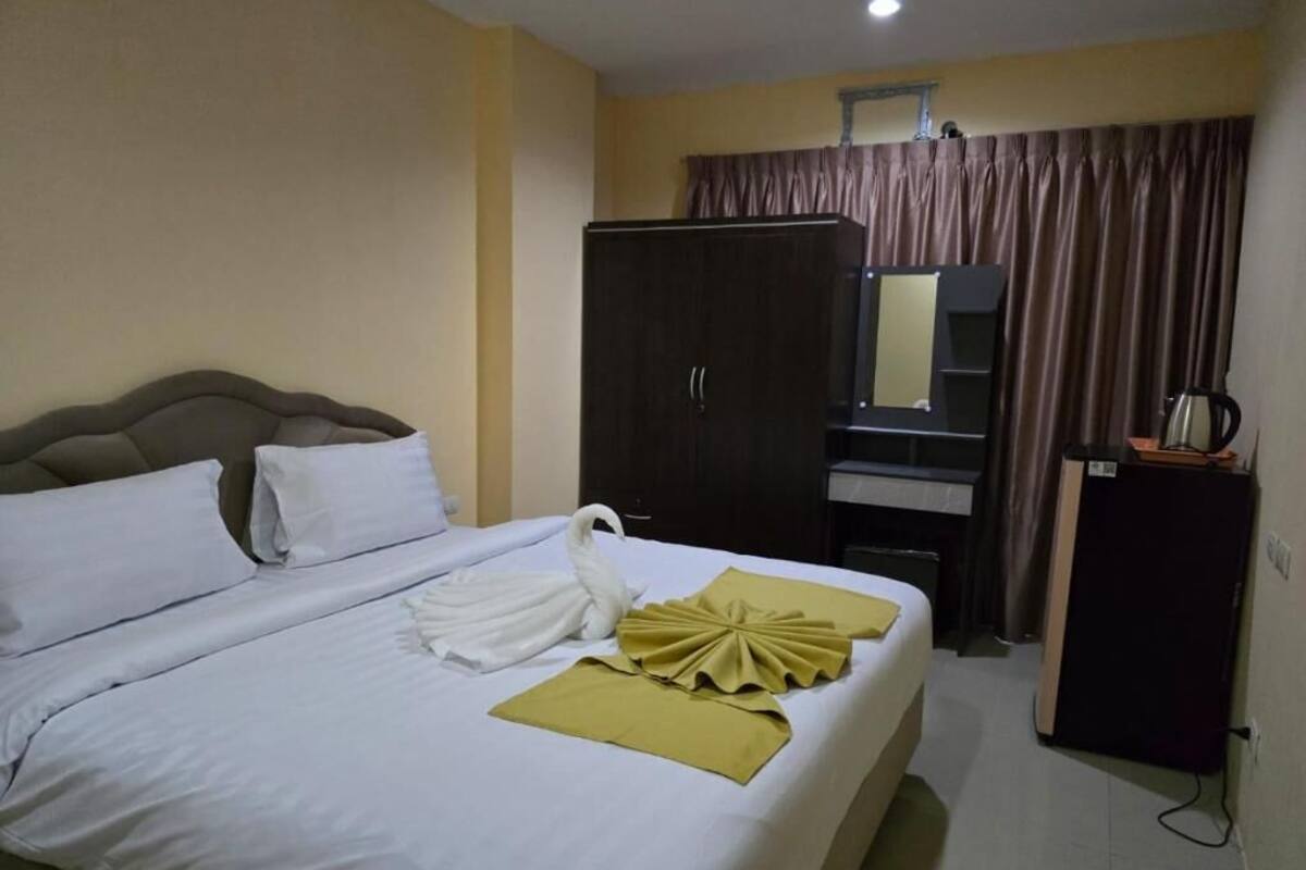 Una habitación de hotel con cama, armario, escritorio y tetera.