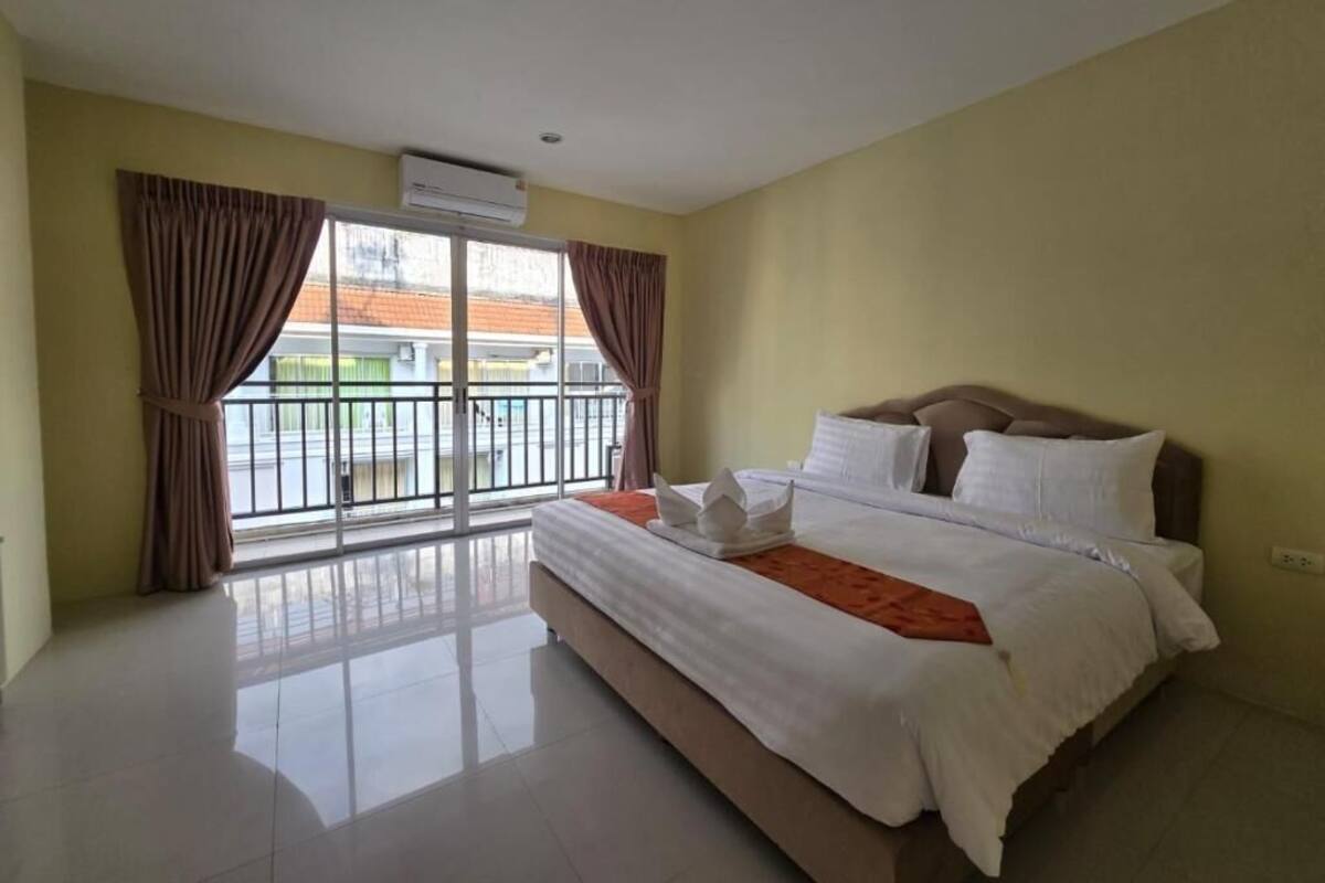 Una habitación de hotel con una cama grande, un balcón con cortinas y un equipo de aire acondicionado.