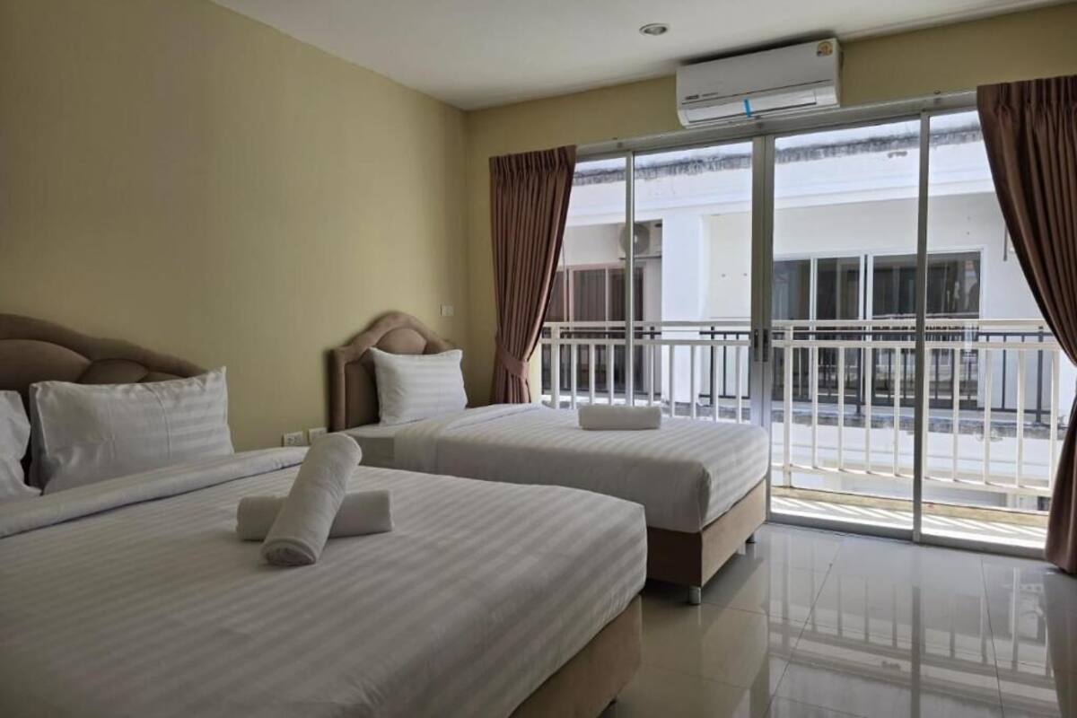 Habitación de hotel con dos camas, un balcón y un equipo de aire acondicionado.