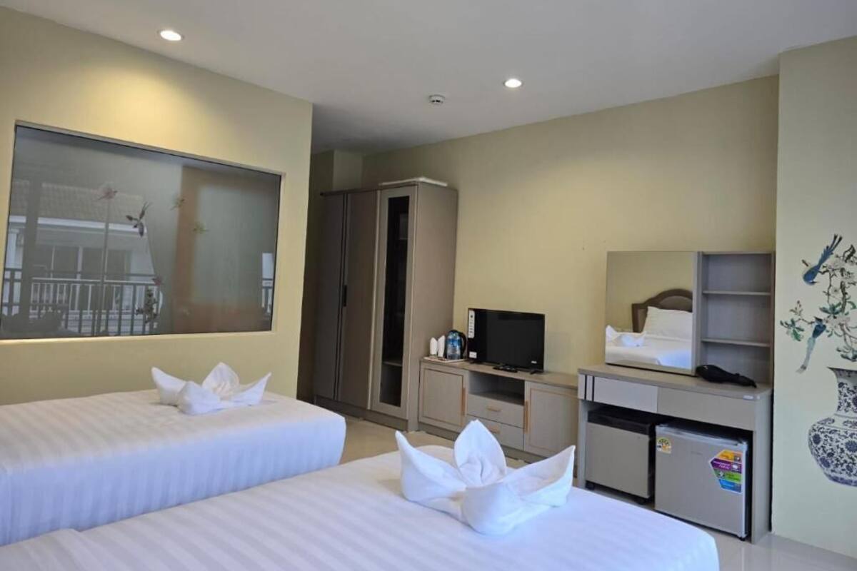 Habitación de hotel con dos camas, televisión, minibar y un amplio ventanal.