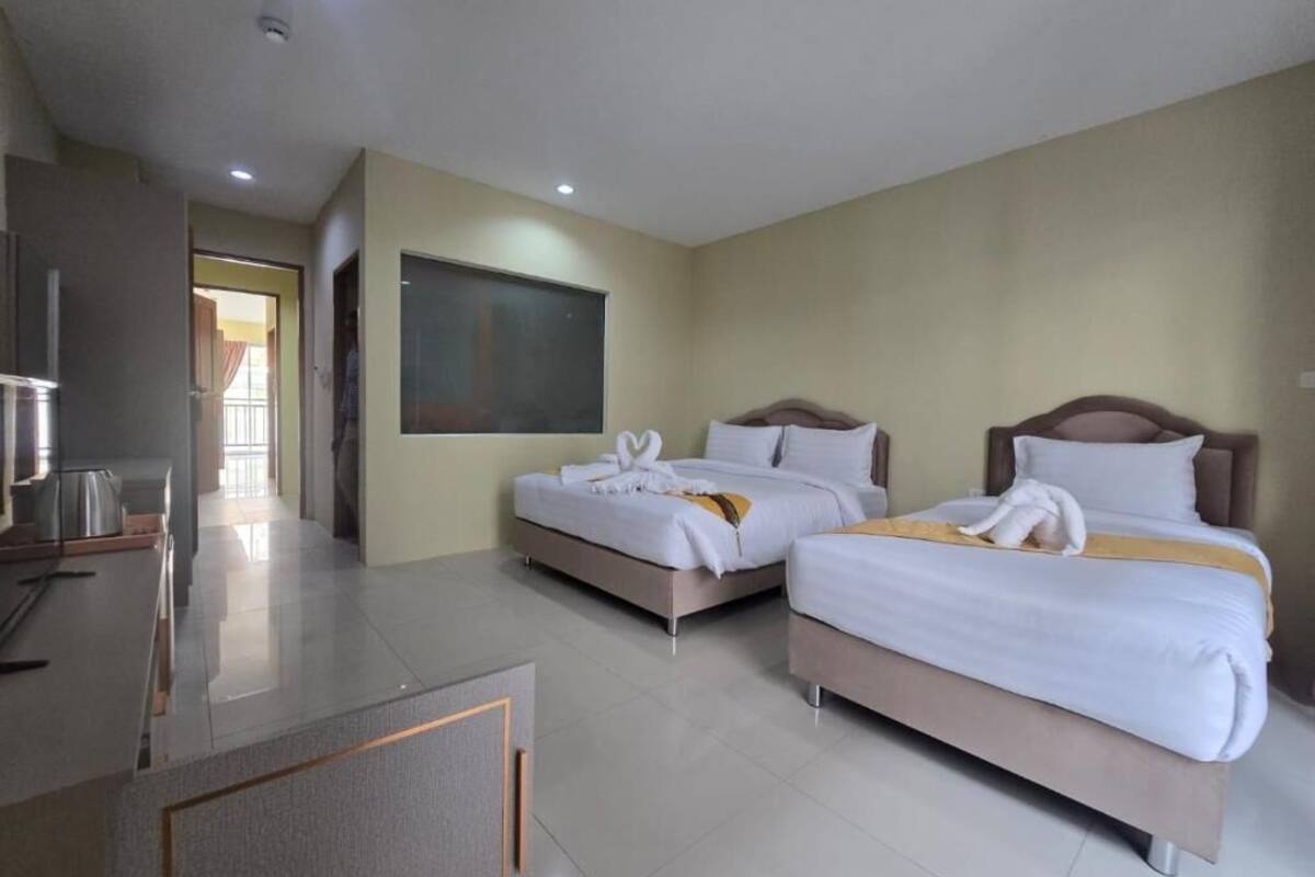 Habitación de hotel con dos camas, televisor de pantalla plana, kitchenette y un ventanal grande.