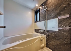 Baño con bañera, ducha y tocador empotrado.