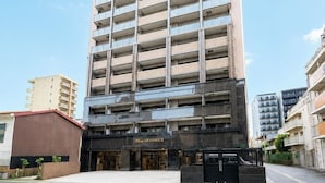 Un hotel de varios pisos con diseño moderno, que destaca por su entrada principal y un estacionamiento frente a él.