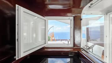 Ein Zimmer mit großem Fenster, Meerblick und Balkon mit einem Stuhl.