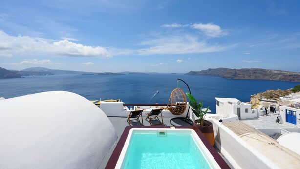 A rooftop pool with a view of the sea, white buildings, and a hanging chair. - Sophia Oia Suites (Oia)