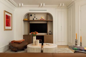 Ein Wohnzimmer mit Kamin, Flachbildfernseher, Sofa, Couchtisch und Bücherregal.