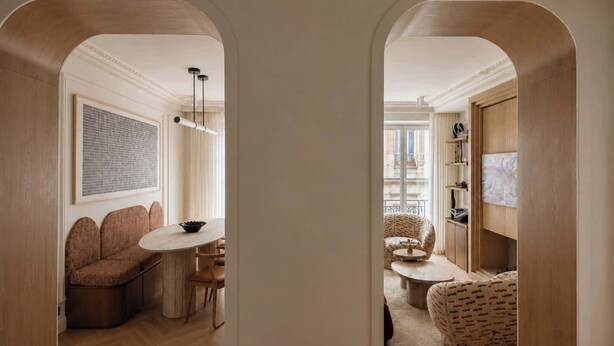 Un intérieur moderne comprenant un coin repas, un espace salon et une vue dégagée sur l’extérieur, accessible par une arche.