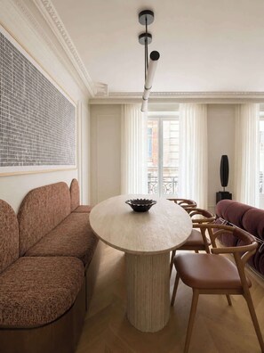 Un salon moderne avec une table ronde, deux canapés et une grande fenêtre avec des rideaux.