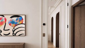 Un couloir avec un lit, un tableau et une porte en bois.