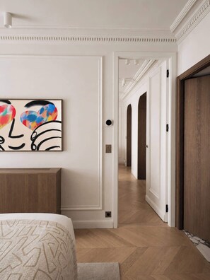 Un couloir avec un lit, un tableau et une porte en bois.