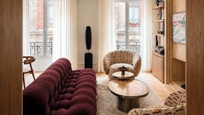 Un salon avec un canapé, un fauteuil, une table basse et un tableau accroché au mur.
