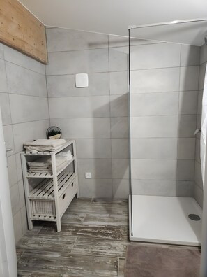 Ett badrum med dusch, en hylla med handdukar och en vägg med träpanel som ger ett snyggt utseende.