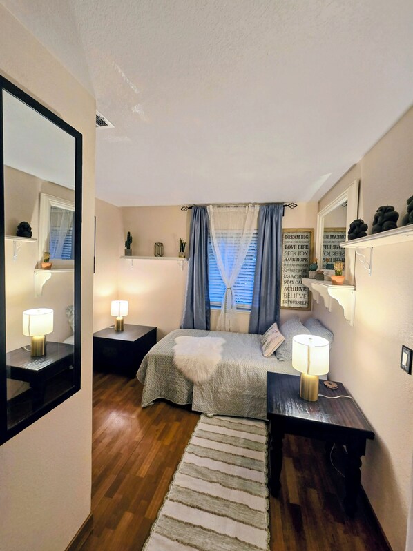 A bedroom with a bed, bedside tables, a mirror, a window with curtains, and motivational wall art. - La Casita Colombiana (Antelope)