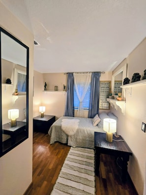 Un dormitorio con cama, mesitas de noche, un espejo, una ventana con cortinas y una decoración mural inspiradora.