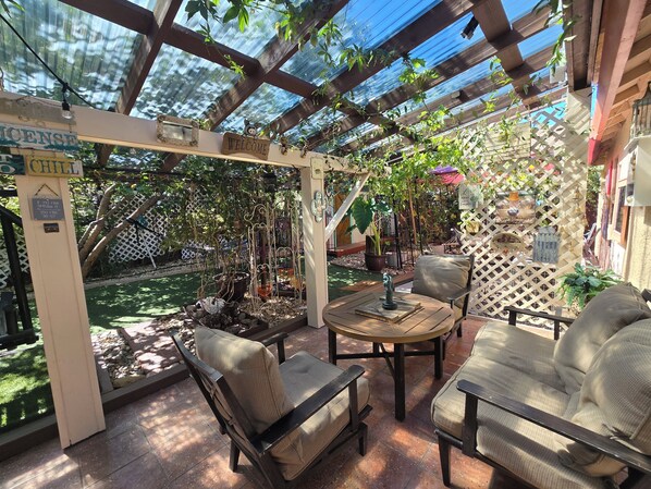 A covered patio area with outdoor furniture, a welcome sign, and a garden view.