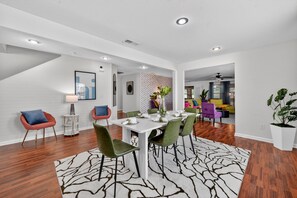 A modern dining area with a white table, green chairs, and a patterned rug. - Southern Comfort Escapes 5br For 14 Near Nasa 5 Bedroom Home (Madison)