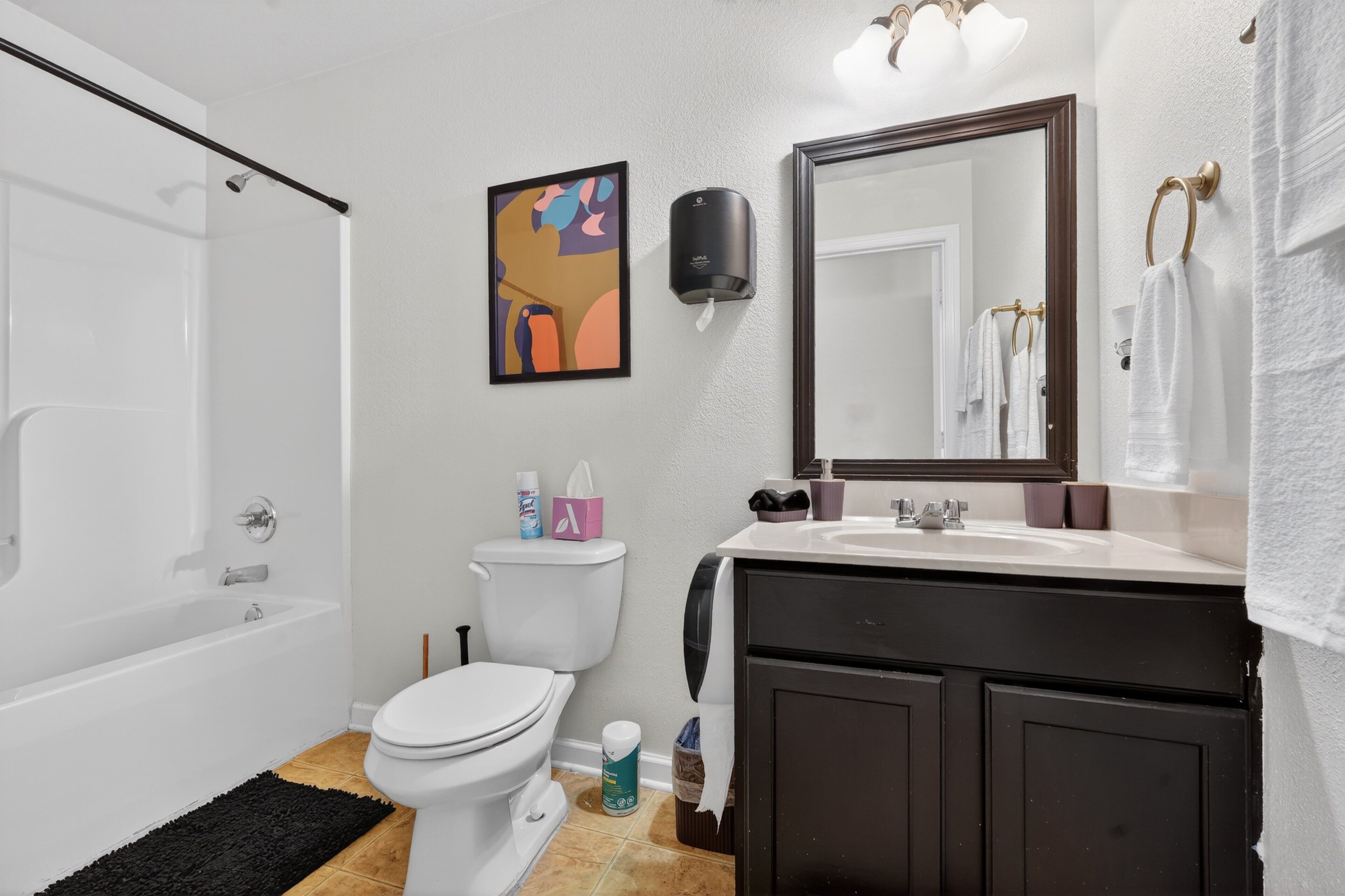 A bathroom with a bathtub, toilet, sink, and a mirror.