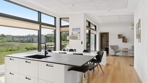 A modern kitchen with a large island, bar stools, and a view of the outdoors. - 4 Star Holiday Home in Allinge (Allinge)