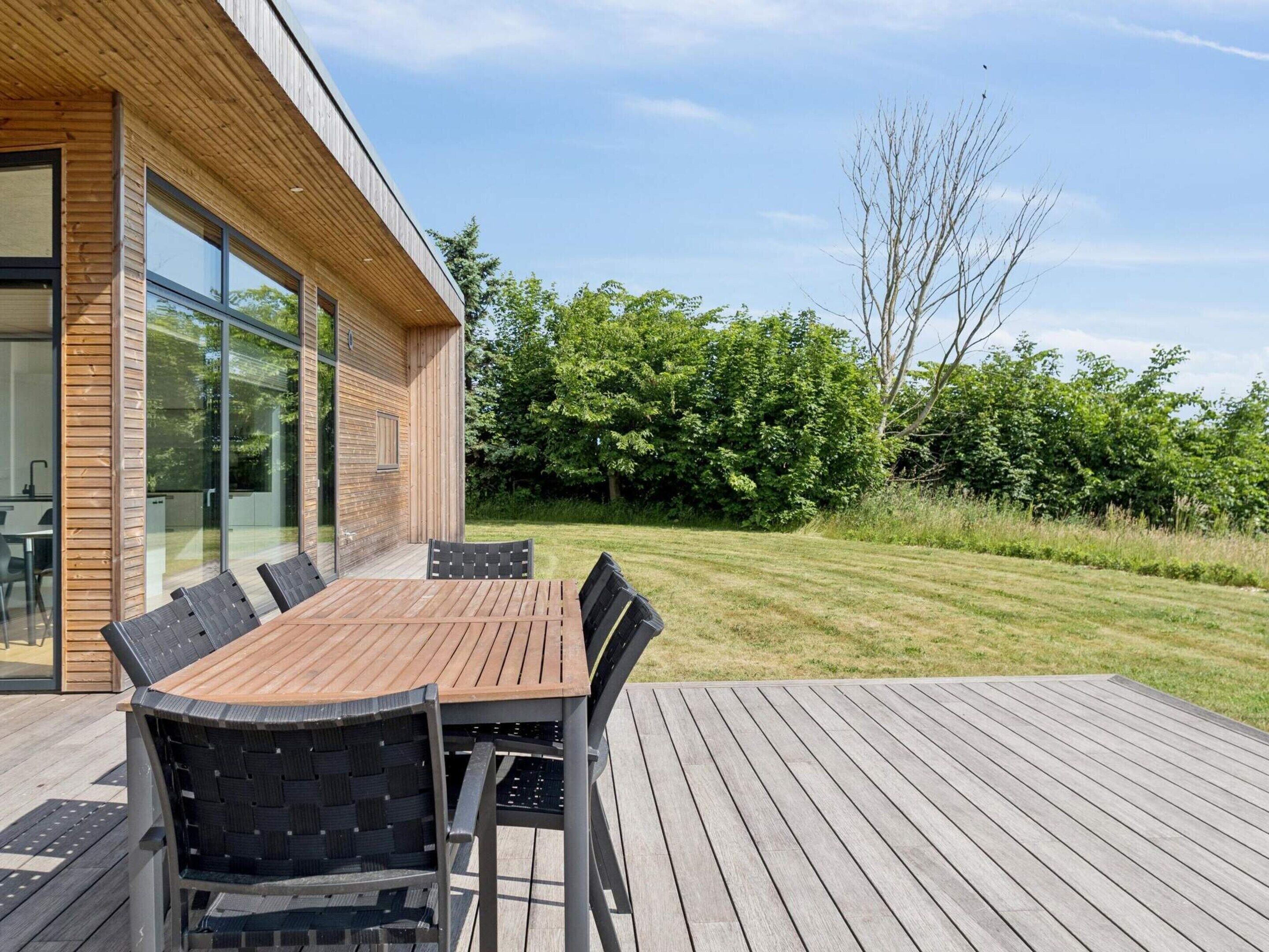 Een modern buitenontbijtgedeelte met een houten terras, een tafel en stoelen.