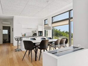 Eine moderne Küche mit Essbereich, großen Fenstern und Blick ins Freie.