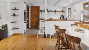 A modern kitchen with wooden cabinets, a central island, and a dining area with wooden chairs. - 4 Star Holiday Home in Borup (Borup)