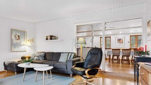 A modern living room with a sofa, a coffee table, a chair, and a dining area with a table and chairs. - 4 Star Holiday Home in Borup (Borup)