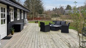 A wooden deck with outdoor furniture, a small table, and potted plants. - 4 Star Holiday Home in Borup (Borup)