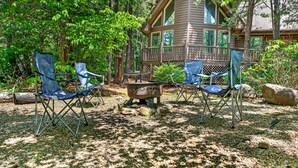 A cabin with a deck, surrounded by trees, and equipped with outdoor seating and a fire pit. - Bear Alley 4 Bedroom Cabin (Gatlinburg)