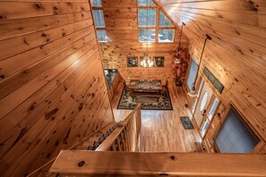 L’intérieur d’un chalet en bois comprend un coin repas, un escalier et de nombreuses fenêtres.