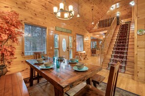 Un intérieur en bois comprenant une table à manger, un escalier et une enseigne sur laquelle on peut lire : « FOI – ESPÉRANCE – AMOUR ».