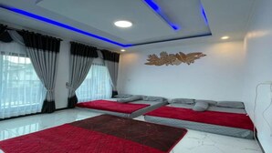 A modern hotel room with a white ceiling, blue LED lighting, a large window with curtains, a bed with red and grey bedding, and a marble floor. - cozzy Salabim Villa Pangalengan (bandung)
