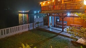 A waterfront property with a wooden deck, outdoor seating, and a view of the water. - cozzy Salabim Villa Pangalengan (bandung)