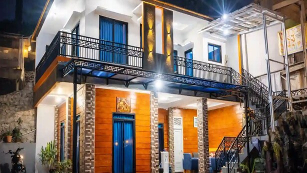 A two-story house with a balcony, a staircase, and a well-lit entrance. - cozzy Salabim Villa Pangalengan (bandung)