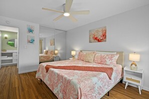 Ein Schlafzimmer mit einem Bett, Nachttischen, einem Deckenventilator und Kunstwerken an den Wänden.