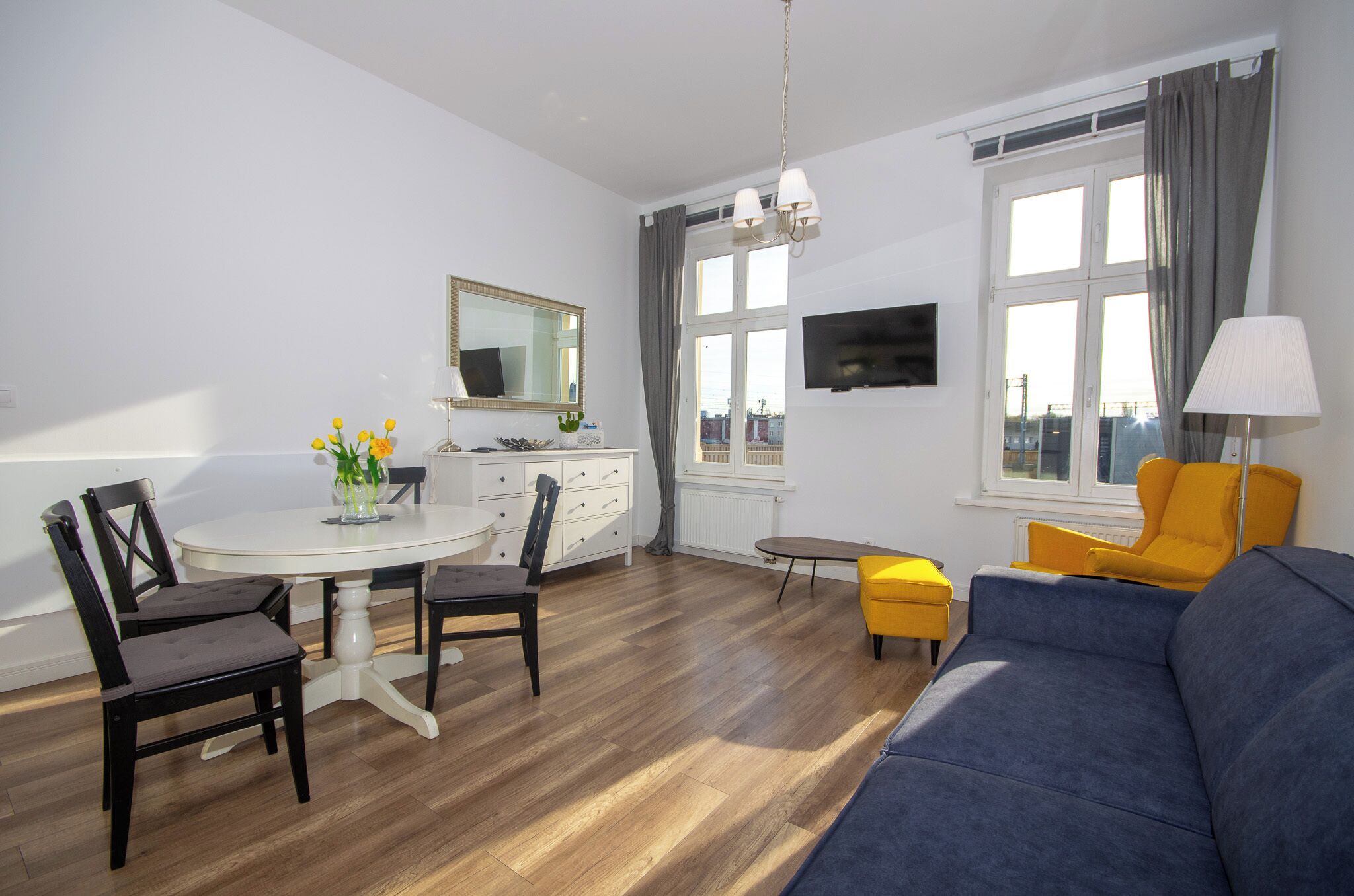 A modern living room with a sofa, chairs, a dining table, and a TV.