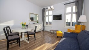 A modern living room with a sofa, chairs, a dining table, and a TV. - InPoint Boutique Apartments near MainSQ (Kraków)