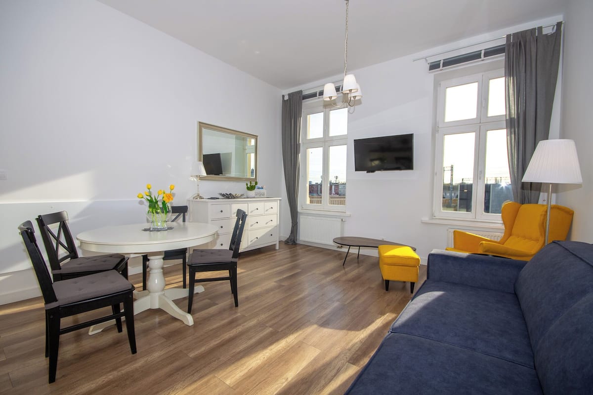 Uma sala de estar moderna com sofá, cadeiras, mesa de jantar e televisão.