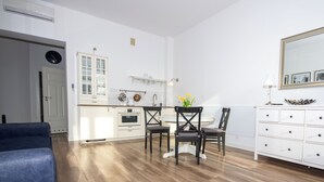 A modern kitchen with white cabinetry, a dining area with two chairs, a white dresser, and a large mirror. - InPoint Boutique Apartments near MainSQ (Kraków)